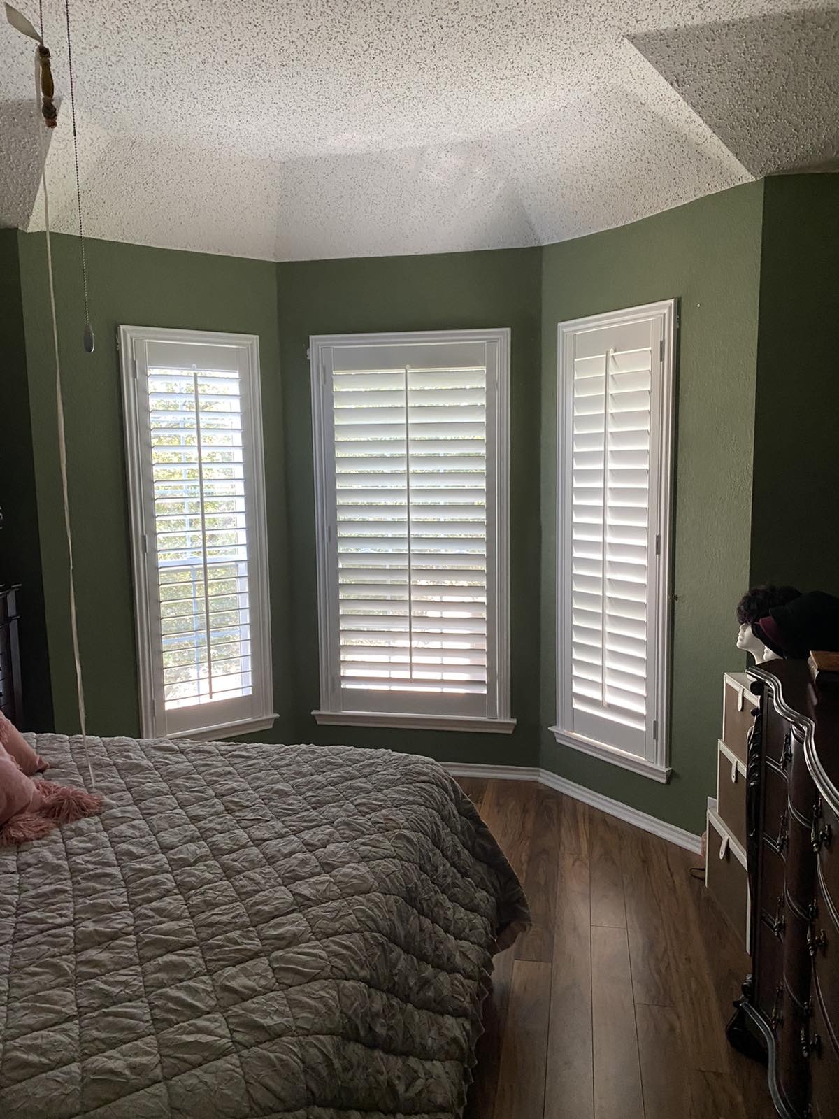 Plantation shutters in a master bedroom bay window
