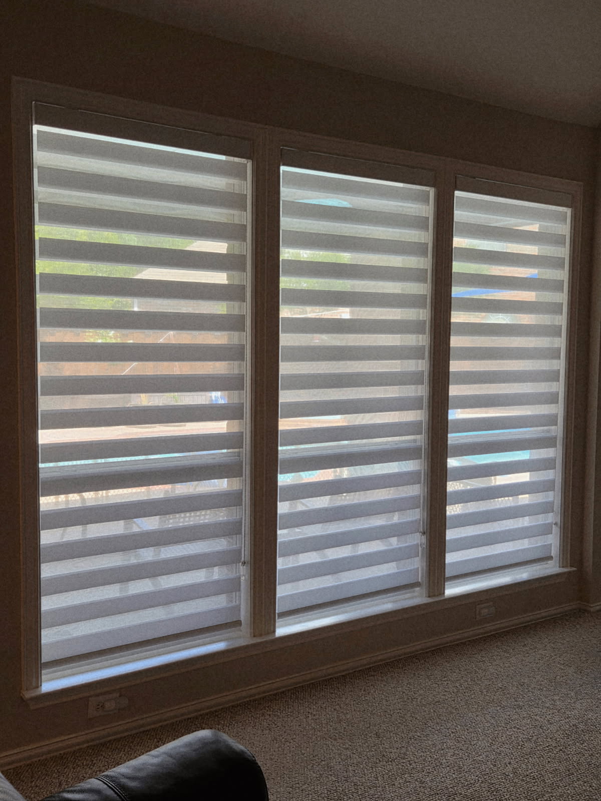 Triple zebra shades covering a large living room window wall