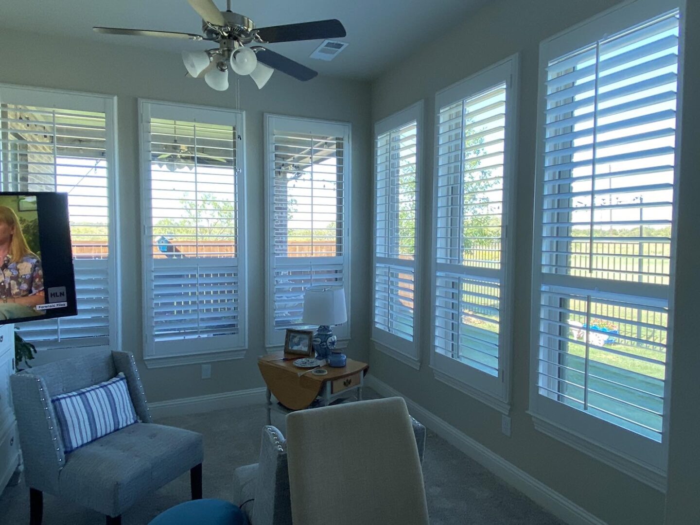 Plantation shutters across a sunroom with a view